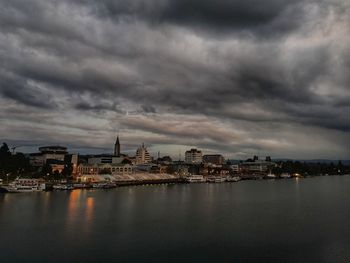 City at waterfront against cloudy sky