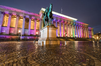 Statue in illuminated city against sky at night