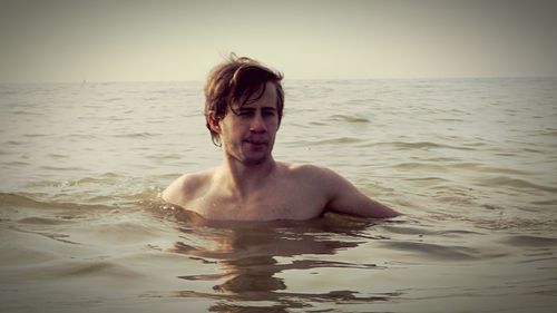 Man swimming in sea against sky