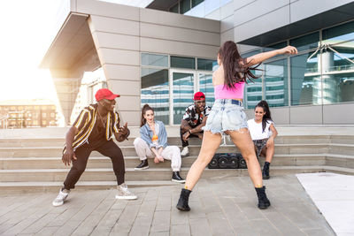 Friends dancing against building in city