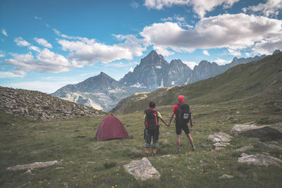 Couple holding hands on mountain against sky