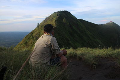 Rear view of man looking at mountain against sky