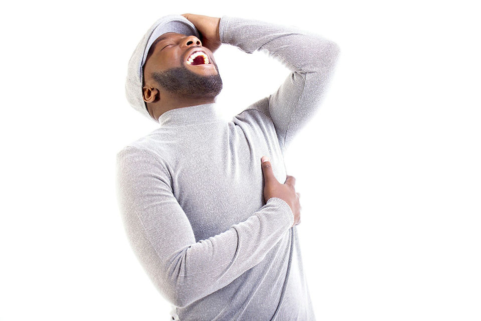 PORTRAIT OF YOUNG MAN STANDING AGAINST WHITE BACKGROUND AGAINST GRAY