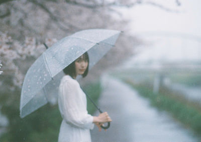 Woman holding umbrella standing in rain