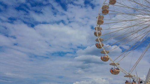 Low angle view of ferris wheel against cloudy sky