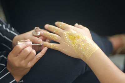 Close-up of woman making henna tattoo on hand of bride