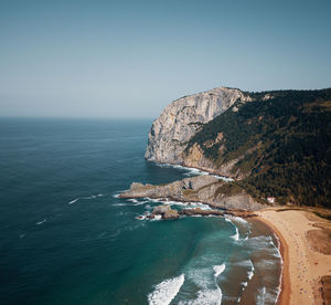 Scenic view of beach and rock against clear sky