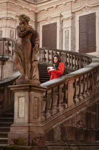 Young woman standing on staircase by railing against building