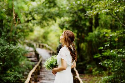 Side view of bride with eyes closed standing in forest