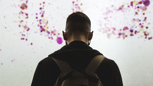 Rear view of man standing against wall