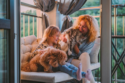 Happy child with smile plays on summer at home with mom, dog at sunset. cat, dog, pets family member