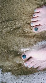 Low section of woman standing at sandy beach