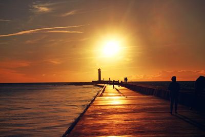 Silhouette pier over sea against sky during sunset