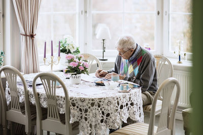 Senior man writing in book at dining table in nursing home