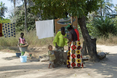 Rear view of people standing against trees