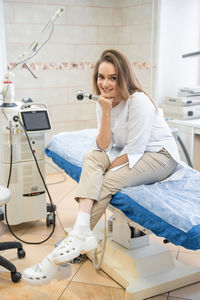 Portrait of young woman using mobile phone while sitting in hospital