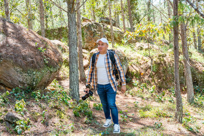 Full length of young woman standing in forest