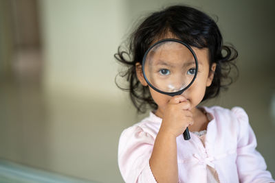 Portrait of girl looking through magnifying glass