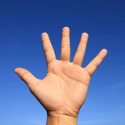 Close-up of human hand against clear blue sky