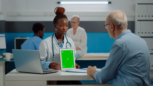 Doctor showing digital tablet to patient in clinic