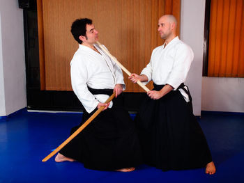 Men fighting with wooden swords on tatami mat