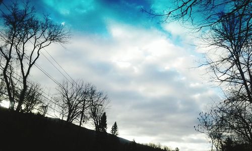 Low angle view of bare tree against cloudy sky