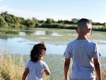 Rear view of siblings standing against sea