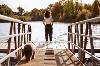 Rear view of woman walking on pier over lake