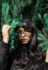 Portrait of young woman with long hair amidst plants