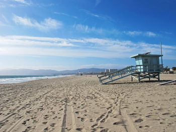 Lifeguard hut at beach against blue sky