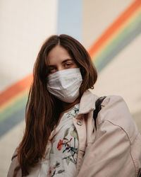 Portrait of beautiful young woman wearing a mask agaisnt buildings 