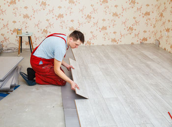 Side view of manual worker making hardwood floor at home