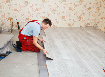 Side view of manual worker making hardwood floor at home