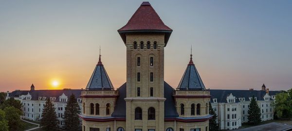 Temple against buildings in city at sunset