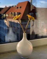 Close-up of flower vase on table against building