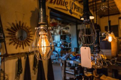 Close-up of illuminated light bulbs hanging from ceiling at night