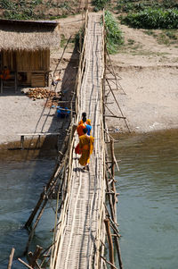High angle view of monks working on footbridge over river