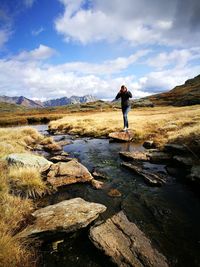 Woman standing on rock against sky