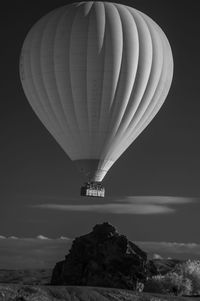 Hot air balloon flying over rocky mountain against sky