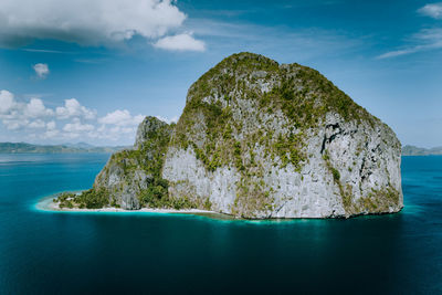 Rock formation by sea against blue sky