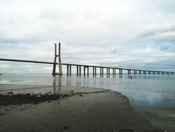 Bridge over calm sea against sky