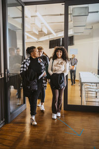 Smiling students leaving classroom while walking together