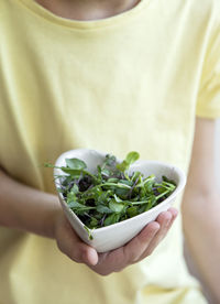 Little girl holding a bowl with microgreens in her hands. healthy eating concept