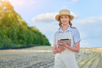 Young woman using phone while standing on field