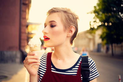 Portrait of young woman holding ice cream in city