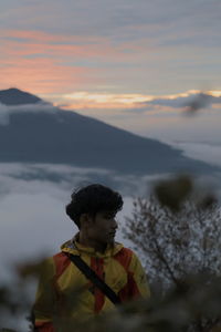 Portrait of boy on mountain against sky during sunset