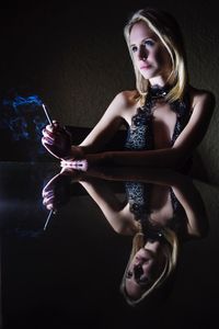 Reflection of thoughtful beautiful woman smoking on table at night
