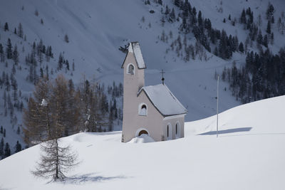 Snow covered buildings by trees and mountains during winter