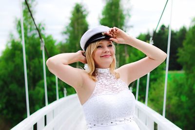 Portrait of smiling young woman standing against plants