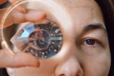 Close-up portrait of woman holding gemstone against eye